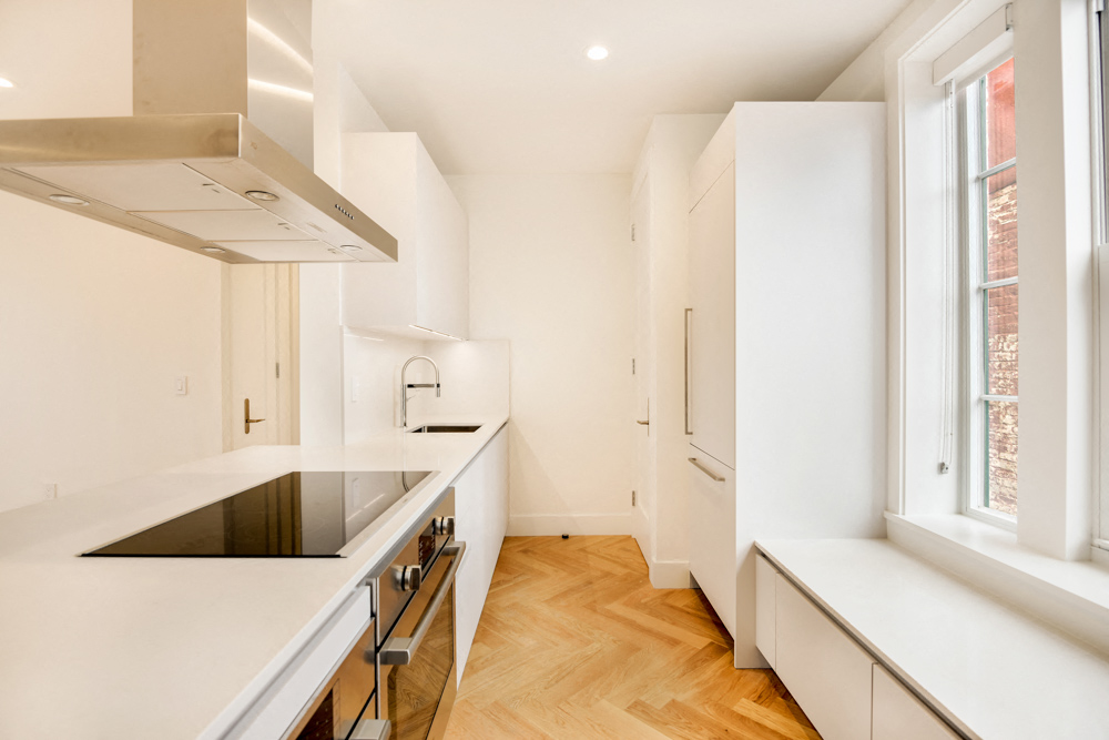 a kitchen with white cabinets and a black counter top and a window